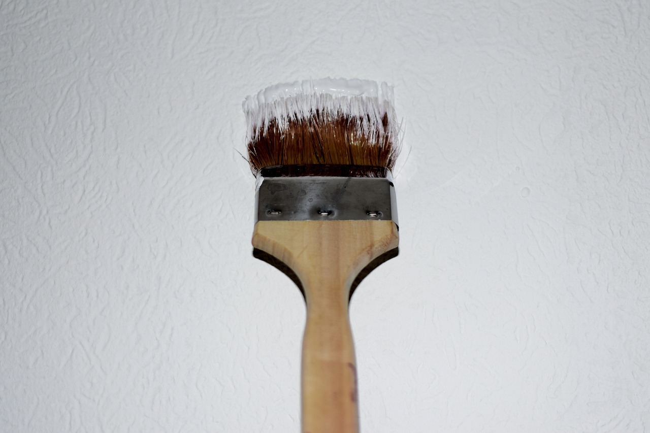 Pinceau appliquant une peinture blanche sur un mur, exemple de finition soignée